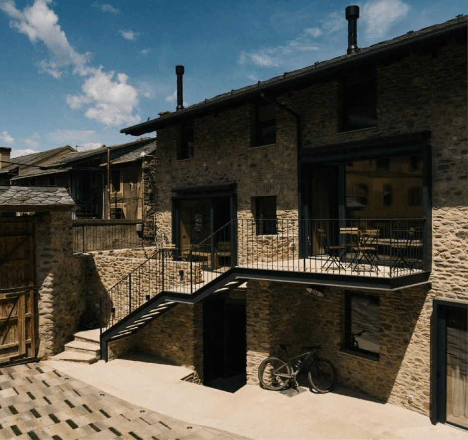 Fachada de piedra de la masía con terraza y escalera exterior