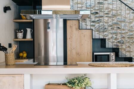 Cocina con frigorífico, microondas y estantes bajo la escalera
