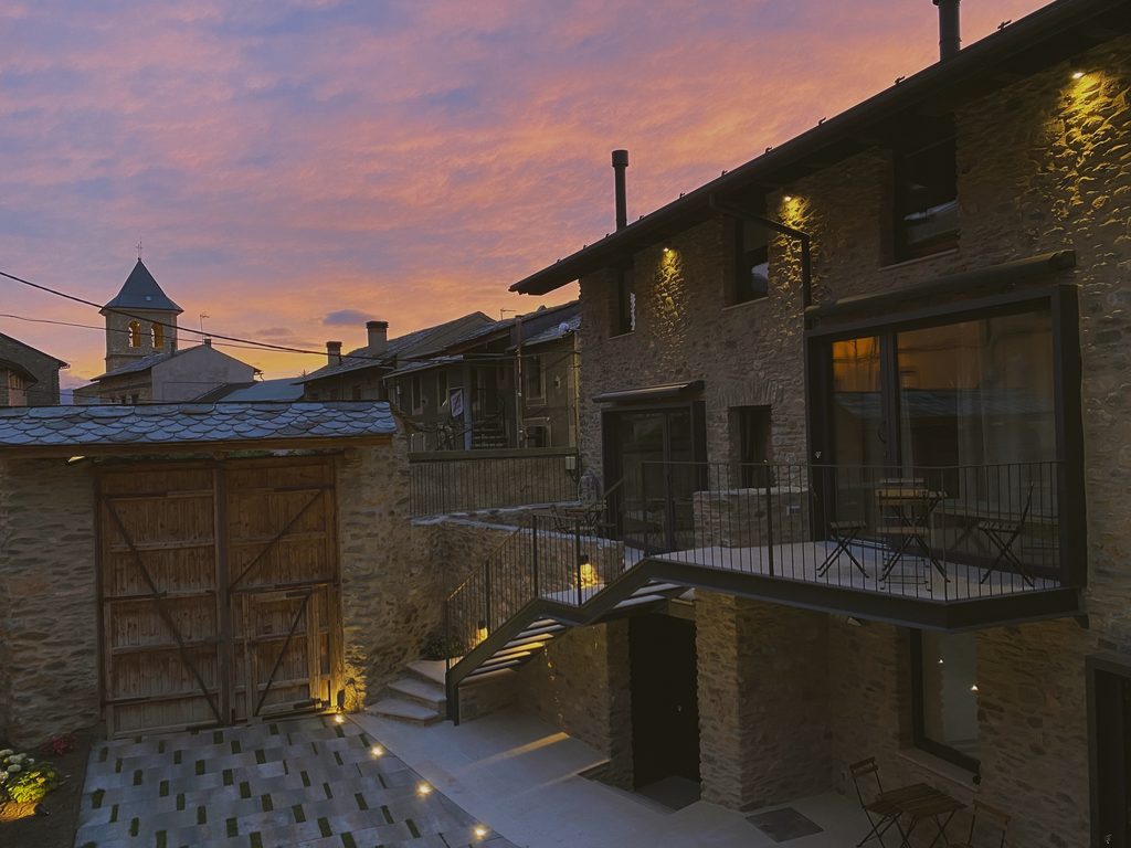 Masía iluminada al atardecer con el campanario al fondo