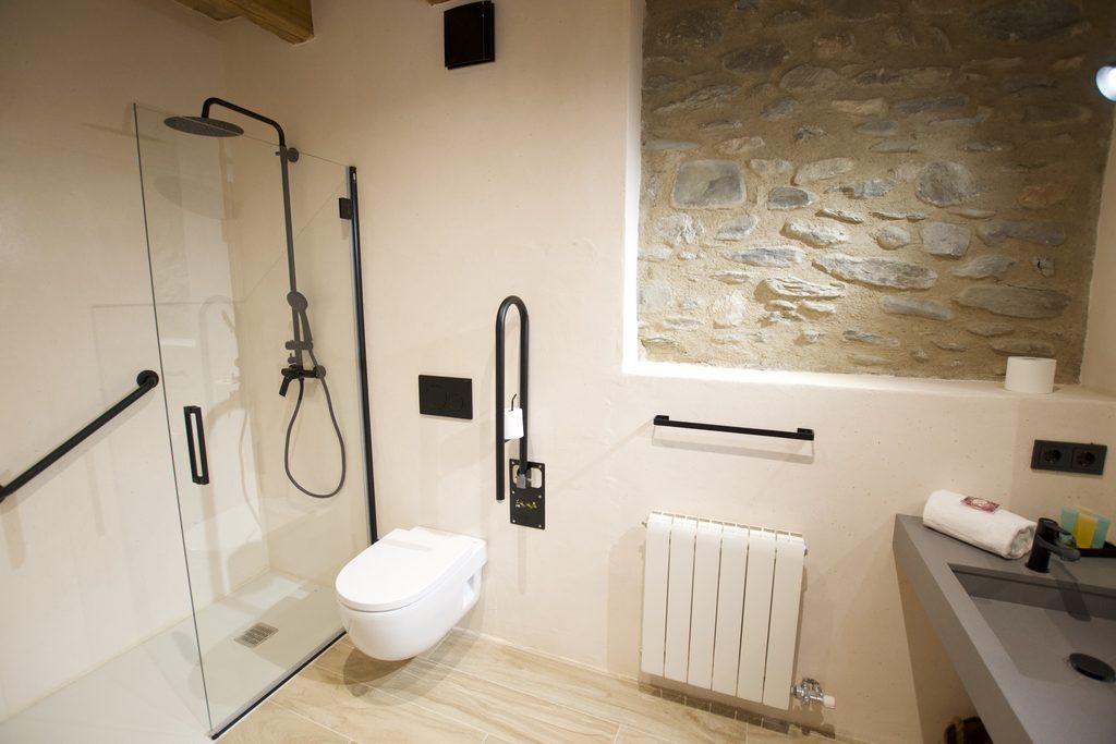 Baño adaptado con ducha a ras de suelo, barras de apoyo e inodoro