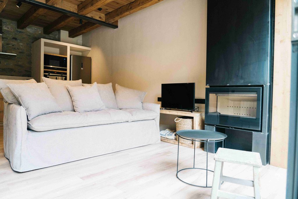 Salón con sofá blanco, televisor y chimenea