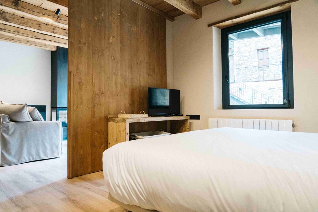 Dormitorio con cama doble, televisor y ventana