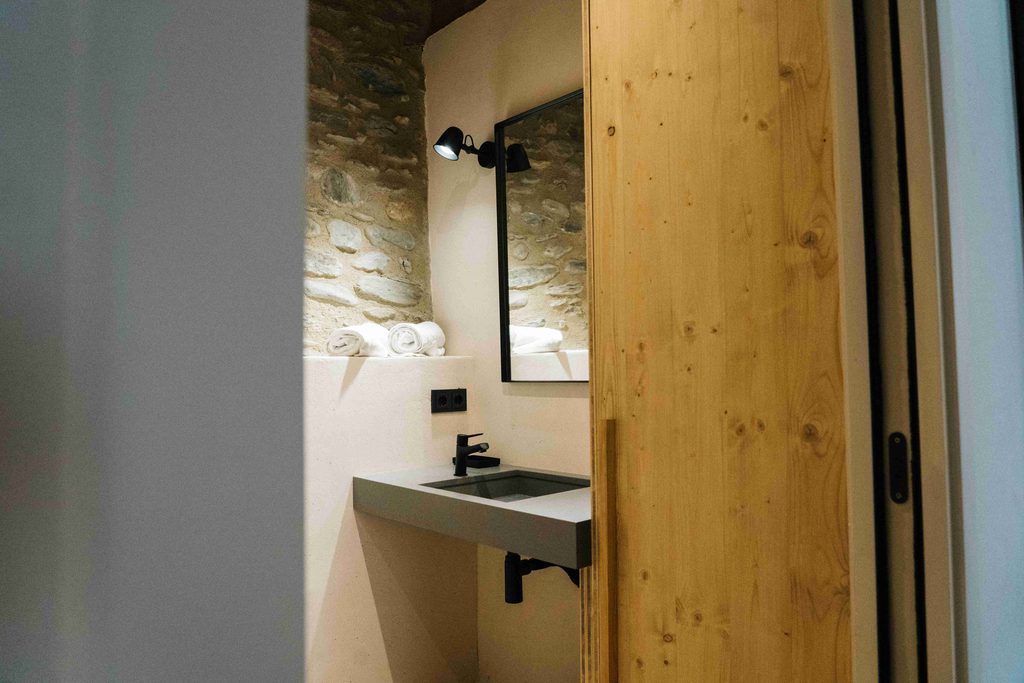 Lavabo junto a una pared de piedra y puerta corredera de madera