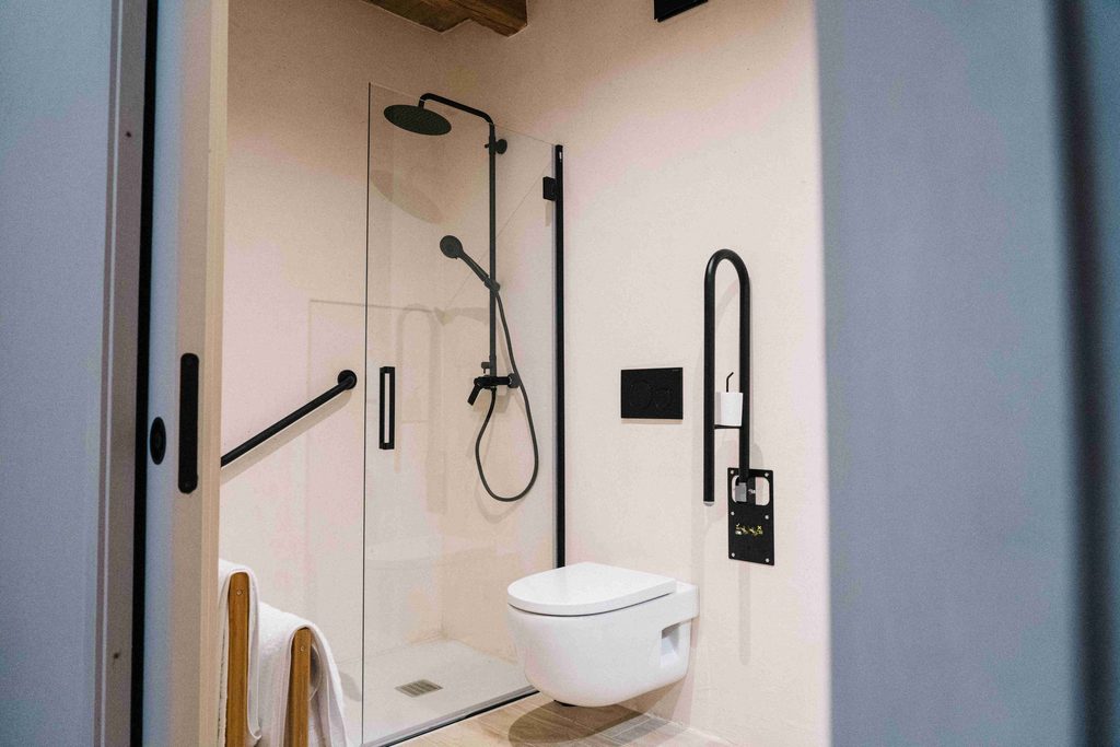 Baño adaptado con ducha, barra de apoyo e inodoro