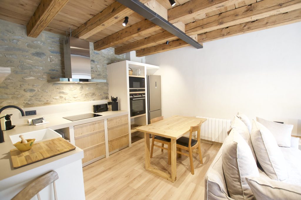 Salón comedor con cocina, mesa de madera y sofá
