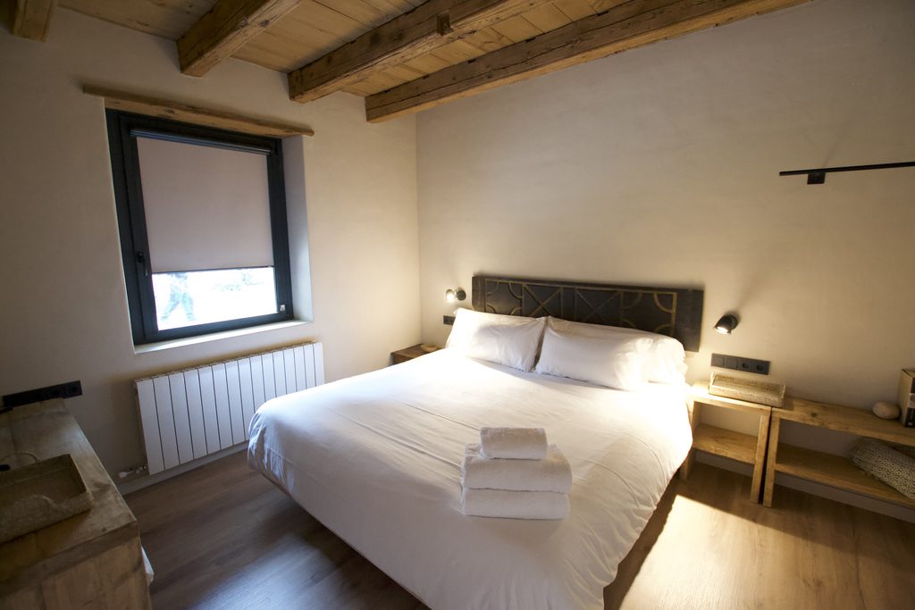 Dormitorio con cama doble y techo de vigas de madera