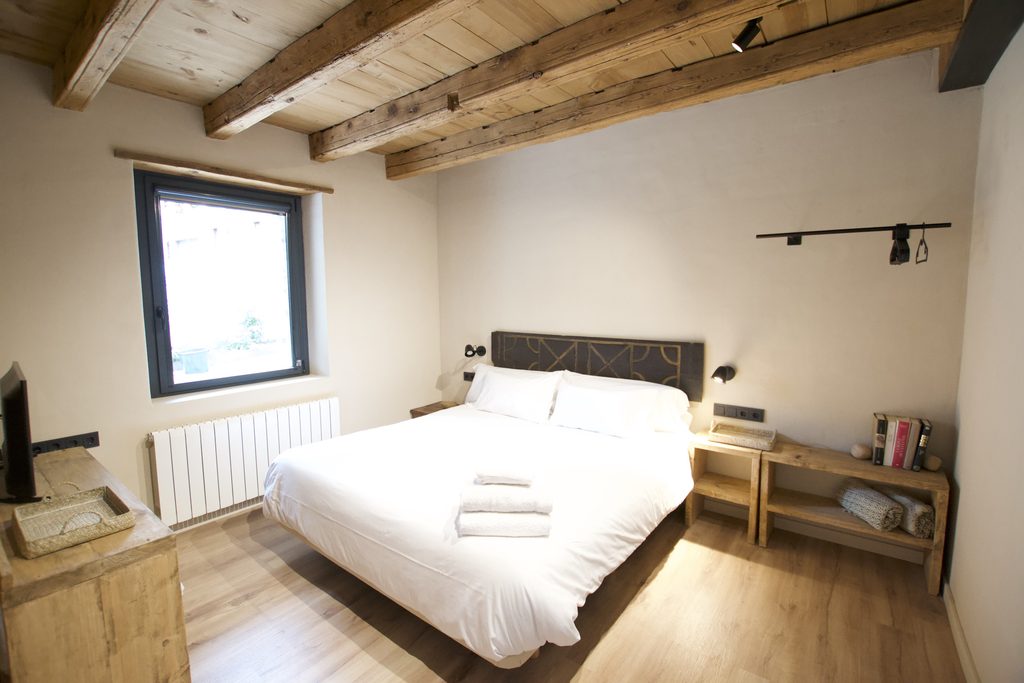 Dormitorio con cama doble, techo de vigas y ventana