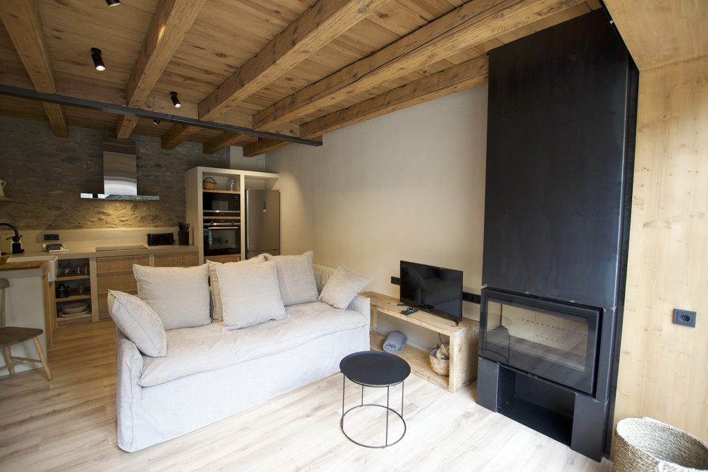 Salón con sofá blanco, chimenea y cocina al fondo