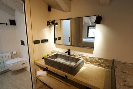 Baño con lavabo de piedra, espejo y encimera de madera
