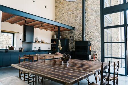 Cocina comedor común con mesa de madera, estufa y ventanales