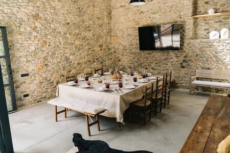Comedor común con mesa puesta, pared de piedra y televisor