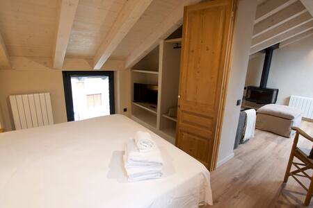 Dormitorio abuhardillado con cama doble y armario de madera