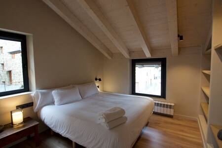 Dormitorio con cama doble y techo de vigas de madera