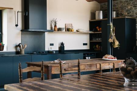 Cocina común con muebles azul oscuro y mesa de madera