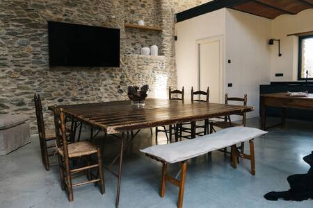 Comedor con mesa de madera, bancos y pared de piedra