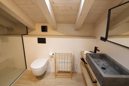 Baño abuhardillado con lavabo de piedra e inodoro