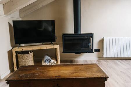 Salón con televisor, estufa de leña y mesa de madera