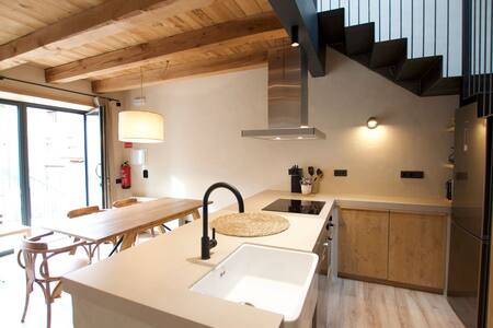 Cocina con fregadero, encimera de madera y mesa bajo la escalera