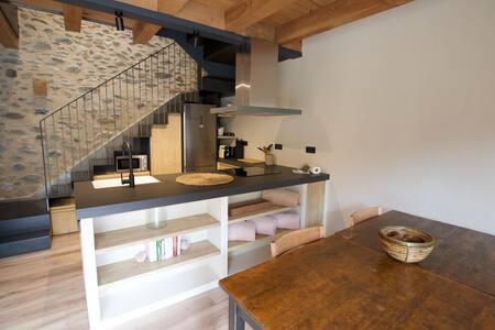 Cocina con isla y mesa de madera junto a una pared de piedra