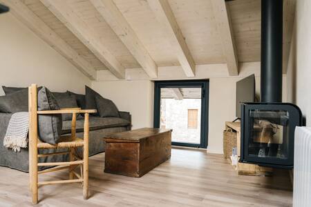 Salón abuhardillado con sofá, baúl de madera y estufa de leña
