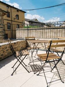 Terraza con mesa y sillas plegables junto a un muro de piedra