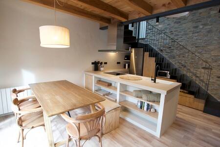 Comedor con mesa de madera, cocina con isla y escalera