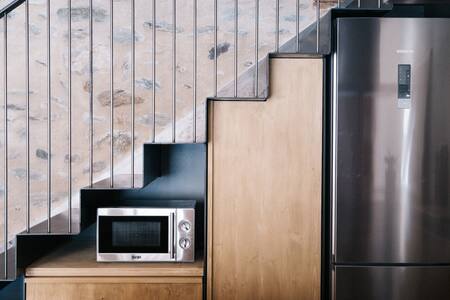 Frigorífico y microondas en un mueble bajo la escalera