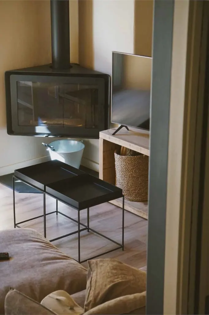 Salón de un apartamento con chimenea de leña, mesa baja y sofá