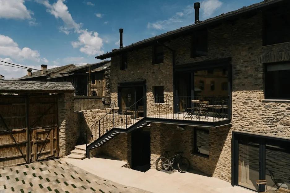 Fachada de piedra de la masía con escalera exterior y terraza